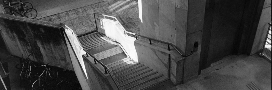 Black and white urban scene with concrete staircase and bicycles in Compiègne, France.